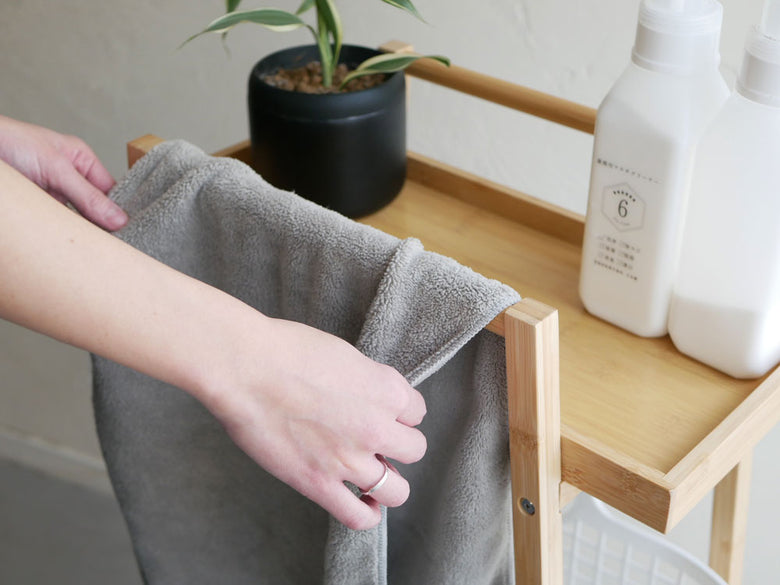 竹製のバンブーランドリーワゴンとポリエチレン製バスケットが家庭の収納棚に整然と配置されている様子