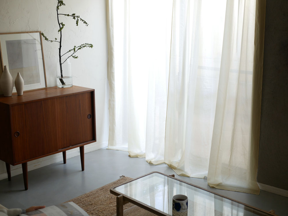 室内の窓に掛かった白いコットン製カーテン