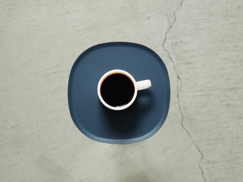 【ideaco/イデアコ】スチールファニュチャー サイドテーブル23、サンドホワイト色のスチール製サイドテーブルの上にカップやソーサーなどのテーブルウェアが配置されている