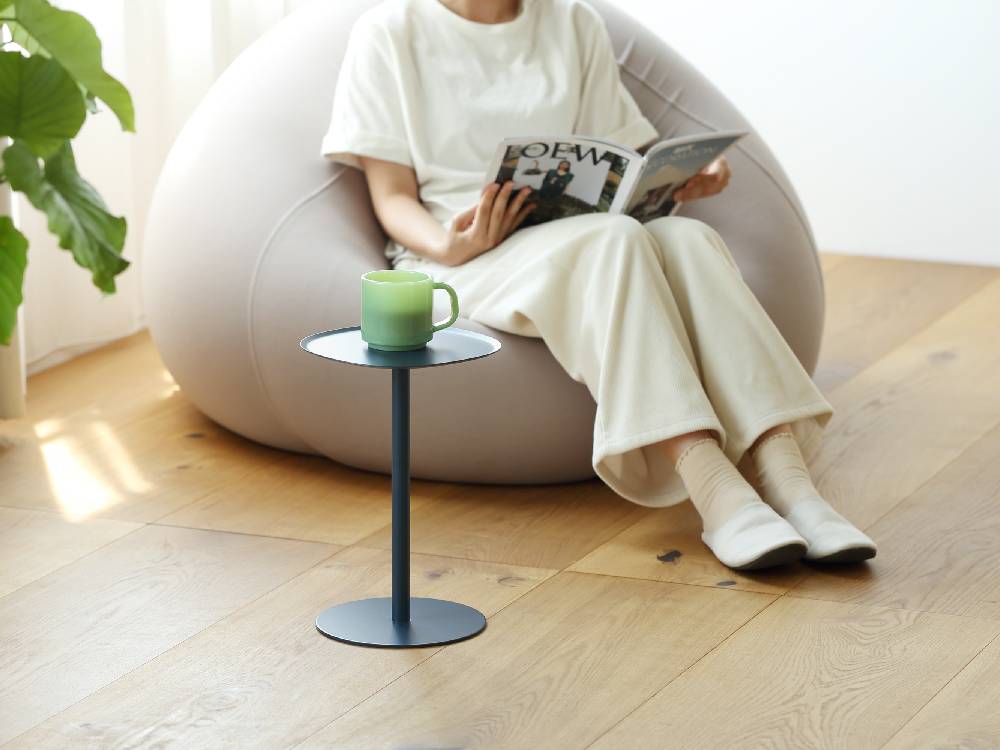 リビングルームに置かれたイデアコのスチール製サイドテーブル23、木製フロアとソファ、コーヒーテーブルと調和