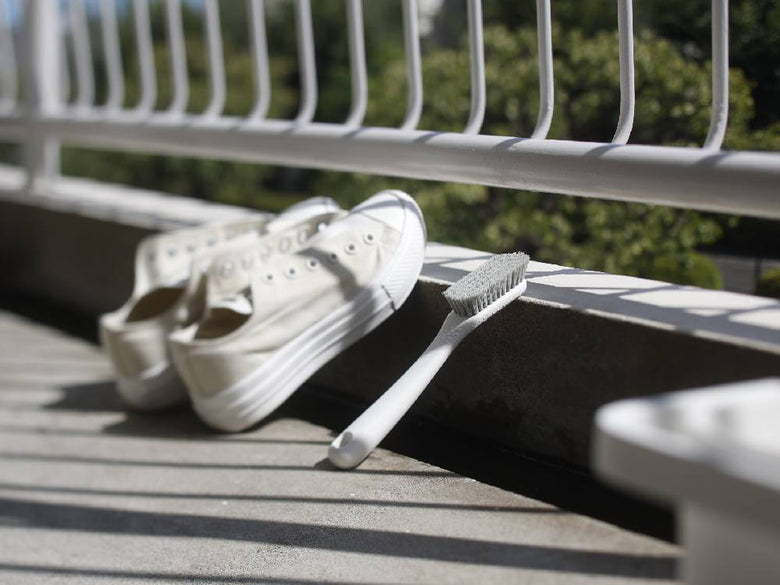 白、グレー、シルバーのポリプロピレン製マーナシューズブラシと屋外用ウォーキングシューズが木製の板の上に置かれた静物写真