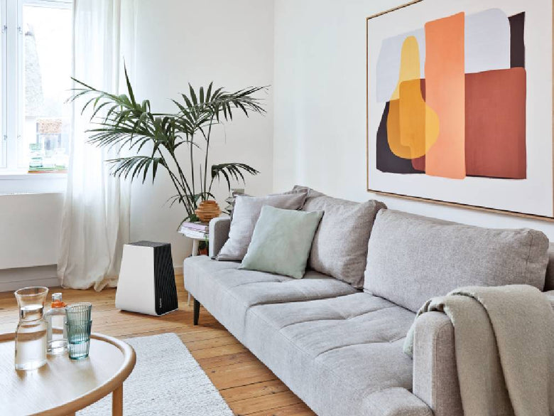 木製フローリングのリビングルームに配置されたソファとテーブルの横に置かれたGeorgeエアウォッシャー空気清浄機