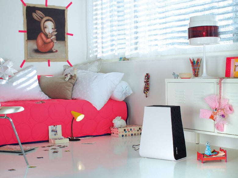 スタドラフォームのGeorgeエアウォッシャーが配置された、ピンクのクッションと照明が調和するおしゃれなリビングルームのインテリア