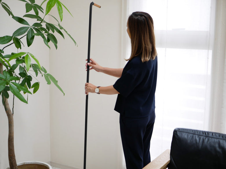 スリムコートハンガーと観葉植物、ランプが配置された室内