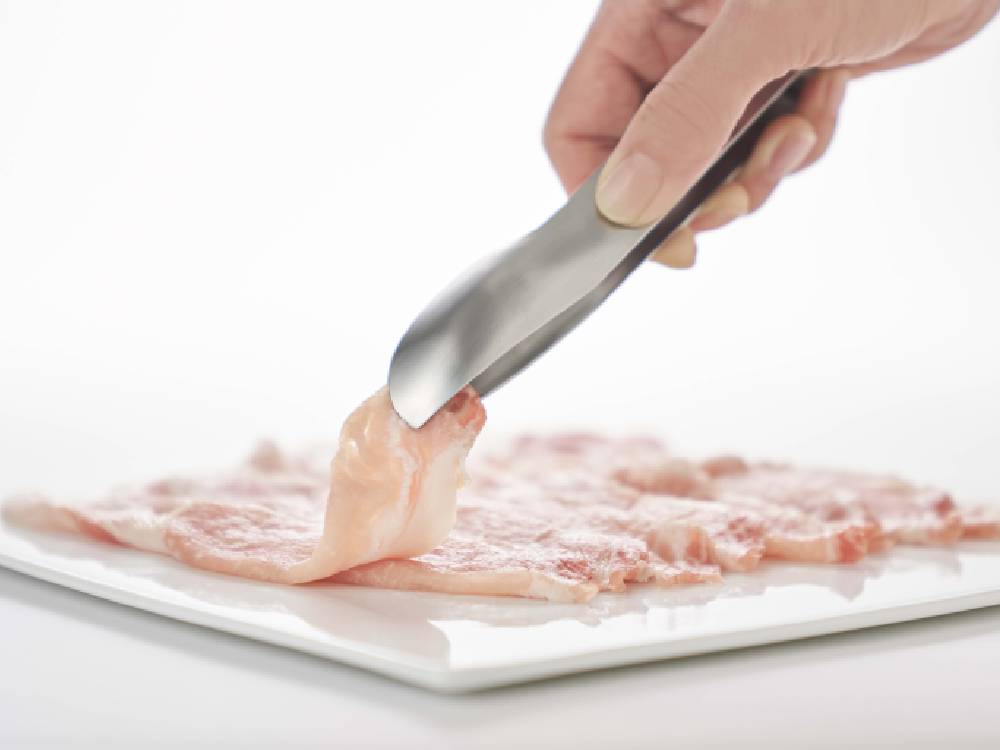 調理中の切り肉とトング、包丁