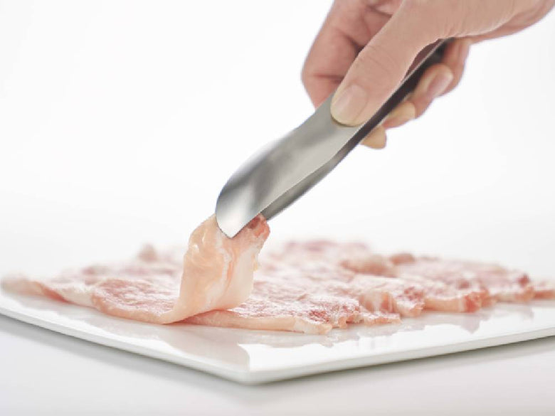 調理中の切り肉とトング、包丁